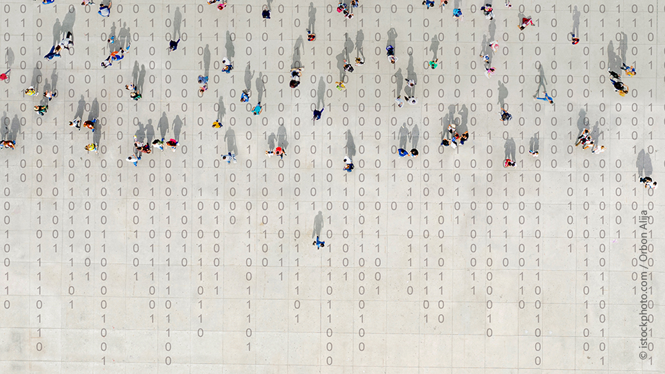 Symbolfoto zeigt eine Wand mit Zahlenfolgen von null bis eins auf denen menschliche Figuren stehen